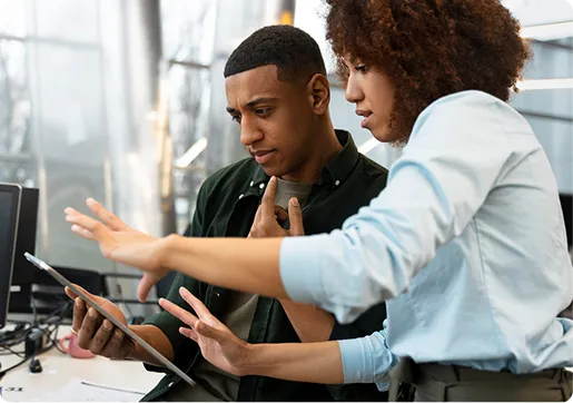 Deux collègues échangeant devant un écran et une tablette